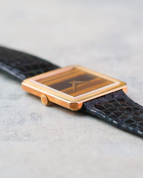 Side view showing the slim profile, reeded bezel and warm tones of the tiger’s eye dial.