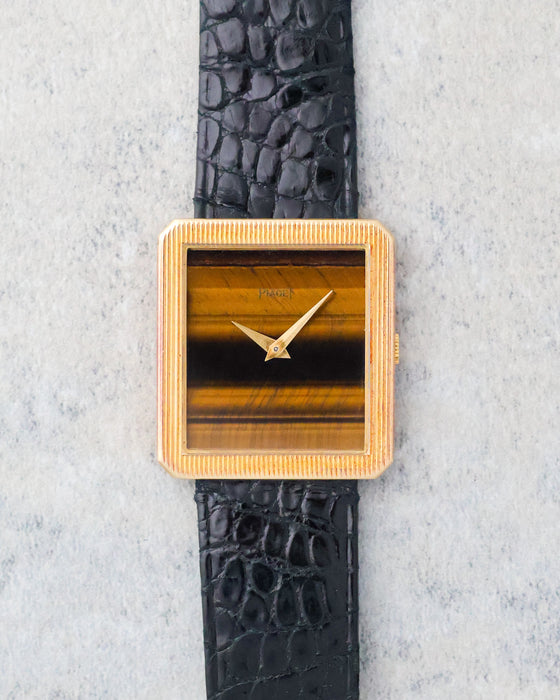 Front view of the Piaget Protocole Ref. 9154 with its striped tiger’s eye stone dial and yellow gold dauphine hands.