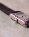 Macro view of the Cartier Tank Allongée crown and pink sapphire-set white gold case.