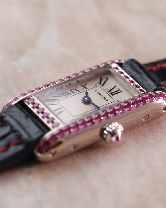Macro view of the Cartier Tank Allongée dial, blued hands and pink sapphire setting.
