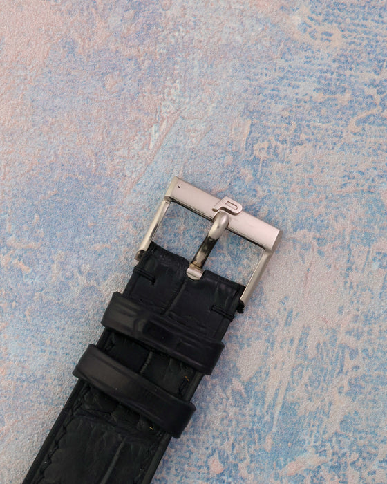 Front view of the signed Piaget white gold pin buckle fitted to the black leather strap.