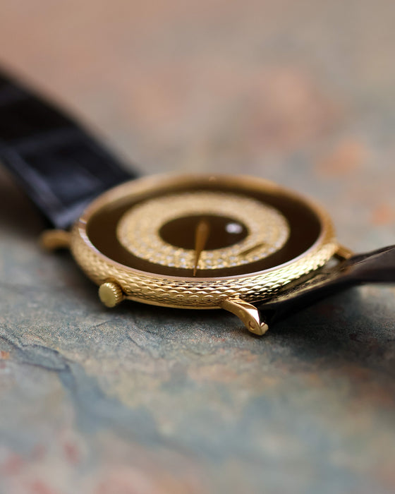 Low-angle view of the Piaget 9026 highlighting the engraved yellow gold case band, crown and black leather strap.