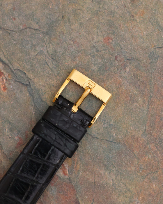 Signed Piaget 18K yellow gold pin buckle fitted to the black leather strap.