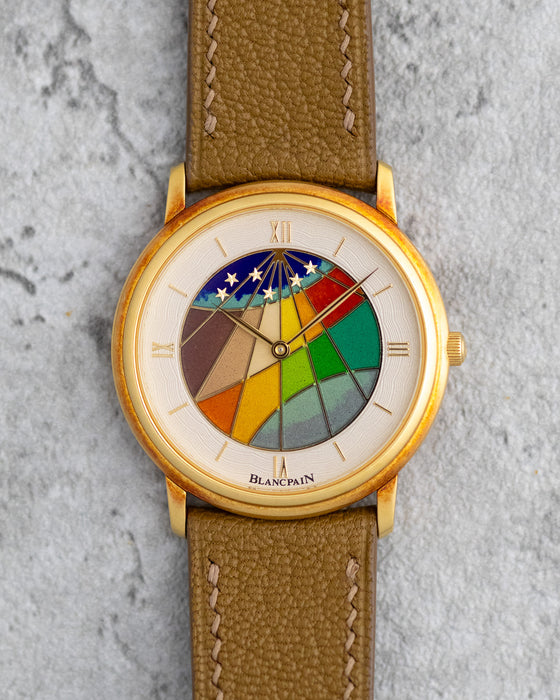 Blancpain Ref. 0021 in 18K yellow gold with colourful cloisonné enamel dial, photographed front-on on a stone background.