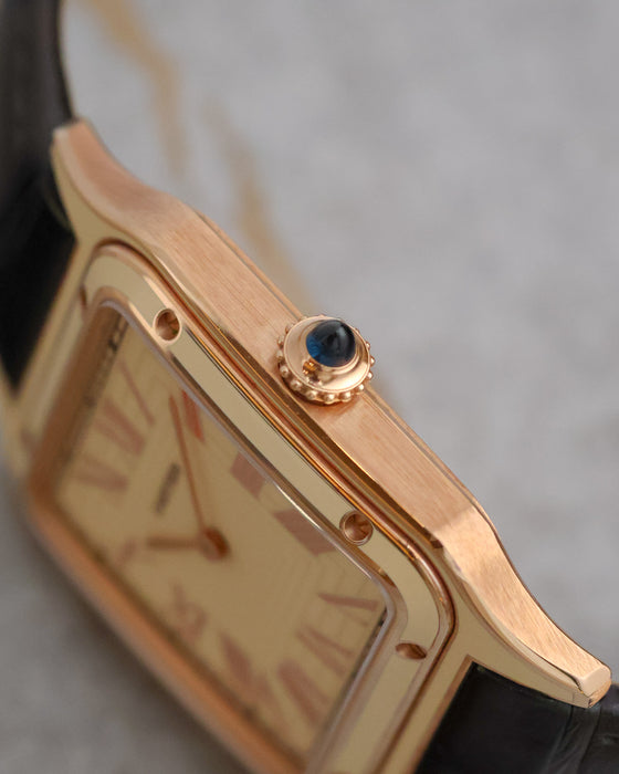 Macro side view of the Cartier Santos-Dumont WGSA0054 showing the brushed rose-gold case and sapphire cabochon crown.