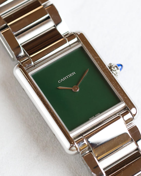 Angled close-up of the green lacquer dial and polished stainless steel case of the Cartier Tank Must WSTA0056.
