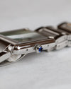 Side profile of the Cartier Tank Must WSTA0056 showing its slim steel case and blue synthetic spinel cabochon crown.