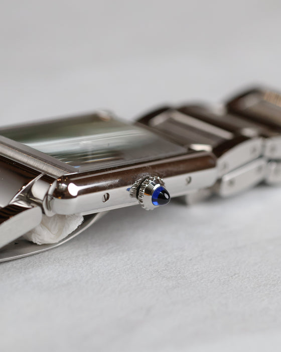 Side profile of the Cartier Tank Must WSTA0056 showing its slim steel case and blue synthetic spinel cabochon crown.