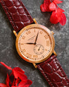 Angled view of the Patek Philippe 5022R showing its pink guilloché dial, rose-gold Roman numerals and burgundy strap.