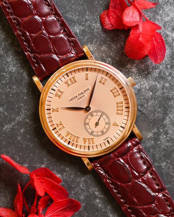 Angled view of the Patek Philippe 5022R showing its pink guilloché dial, rose-gold Roman numerals and burgundy strap.