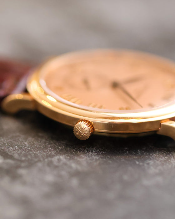 Macro view of the signed crown and slim polished rose-gold case of the Patek Philippe 5022R.