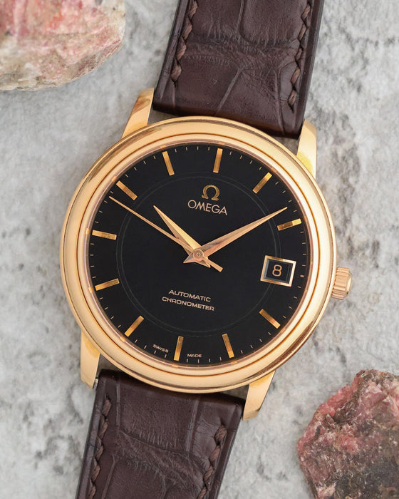 Omega De Ville Prestige in 18K rose gold with black dial, applied gold markers and date at 3 o'clock.
