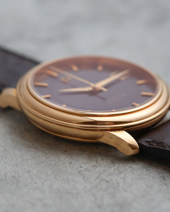 Side profile of the 18K rose-gold Omega De Ville showing its stepped bezel and tapered lugs.