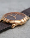 Side view of the polished 18K rose-gold case and curved lugs.