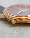Close-up of the signed Omega crown and polished rose-gold case.