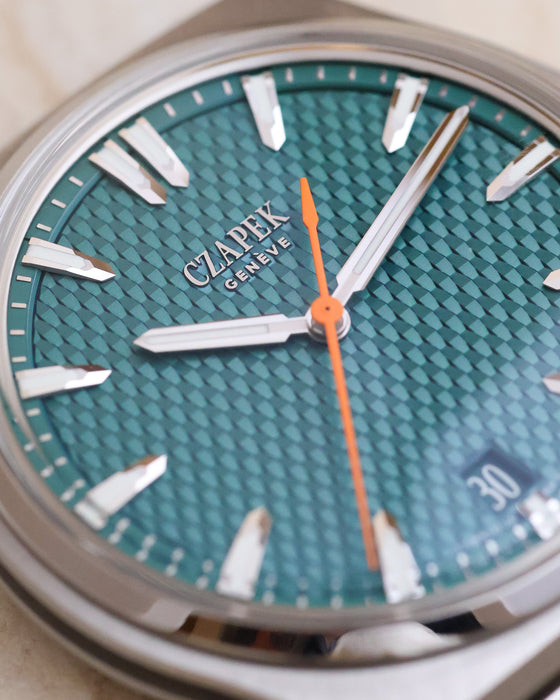 Macro photograph of the Viridian Green flinqué dial with applied indices and full-orange seconds hand.