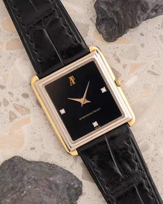 Angled view of the vintage Audemars Piguet showing its black dial, three diamond markers and contrasting yellow and white gold case.