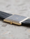 Crown-side profile of the Audemars Piguet rectangular watch showing its yellow gold case, white gold stepped bezel and black dial.