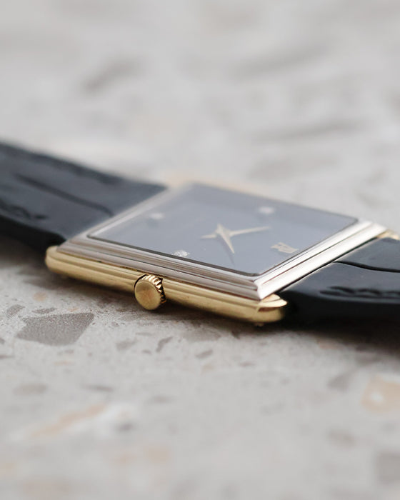Crown-side profile of the Audemars Piguet rectangular watch showing its yellow gold case, white gold stepped bezel and black dial.
