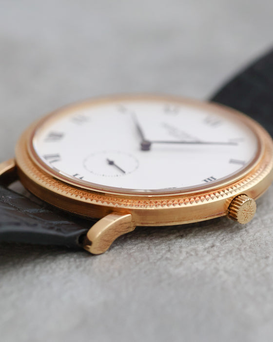 Side profile of the yellow gold Calatrava 3919J showing its slim case, hobnail bezel and signed crown.