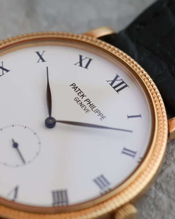 Macro view of the white dial, black Roman numerals and leaf-shaped hands of the Patek Philippe Calatrava 3919J.