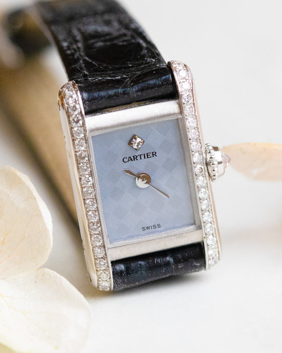 Front close-up of the Cartier Mini Tank featuring a pale blue chequered dial, diamond hour marker and diamond-set case sides.