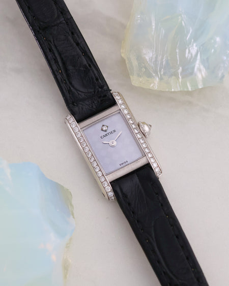 Full angled view of the Cartier Mini Tank in white gold with diamond-set brancards and black leather strap.