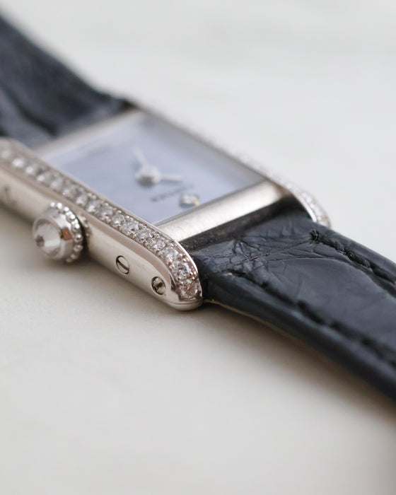 Detailed side view of the Cartier Mini Tank showing the diamond-set crown, polished white gold case and chequered dial.