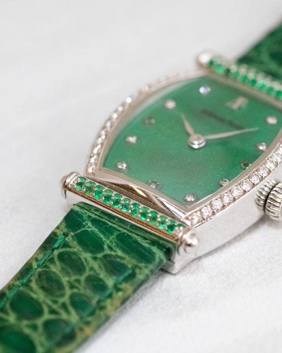 Macro photograph of the green gemstone-set bar, diamond-set bezel and textured green leather strap.