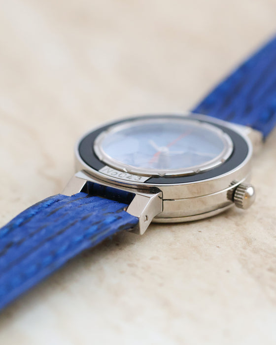 Low-angle profile showing the layered stainless steel case, raised crystal and numbered bezel plaque.