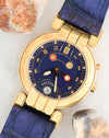 Angled dial photograph of Harry Winston Greenwich GMT showing its blue dial, red-accented GMT hand and date window.