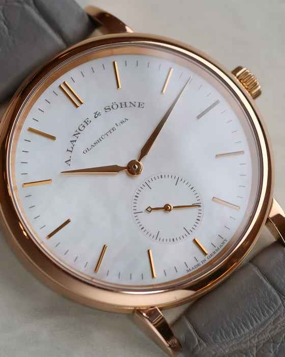 Macro photograph of the white mother-of-pearl dial with applied rose gold hour markers and subsidiary seconds.