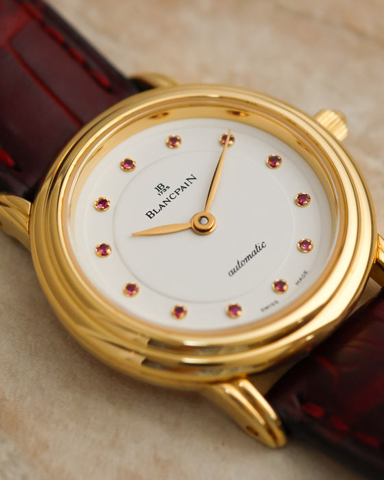Angled close-up of the Blancpain Lady Villeret dial featuring twelve pink gemstone indices in gold settings and slim gold hands.