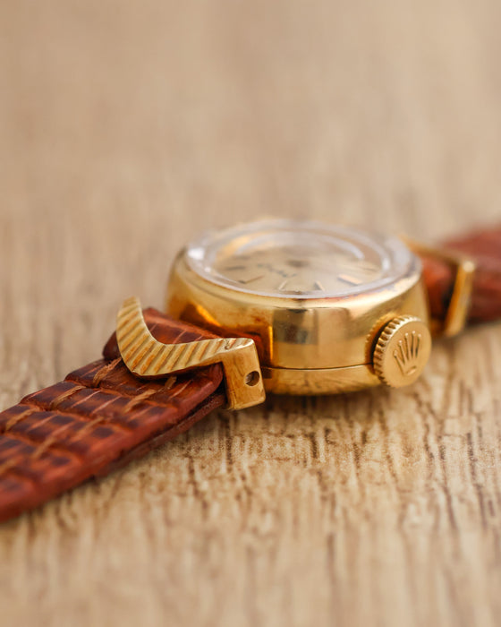 Side profile of the Rolex Orchid showing its faceted crystal, polished yellow gold case, fluted crown and sculpted lug.
