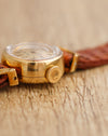 Macro photograph of the Rolex Orchid's signed winding crown, rounded case and raised crystal.