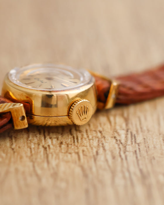 Macro photograph of the Rolex Orchid's signed winding crown, rounded case and raised crystal.