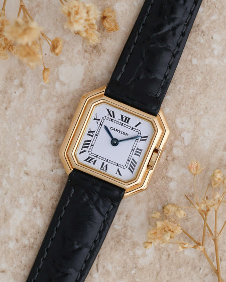 Angled overhead photograph of the Cartier Ceinture 6602 showcasing its stepped gold case and blued steel hands.