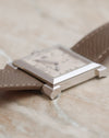 Low-angle photograph emphasising the slim profile and faceted corner lugs of the 18K white gold Carrée Historique.