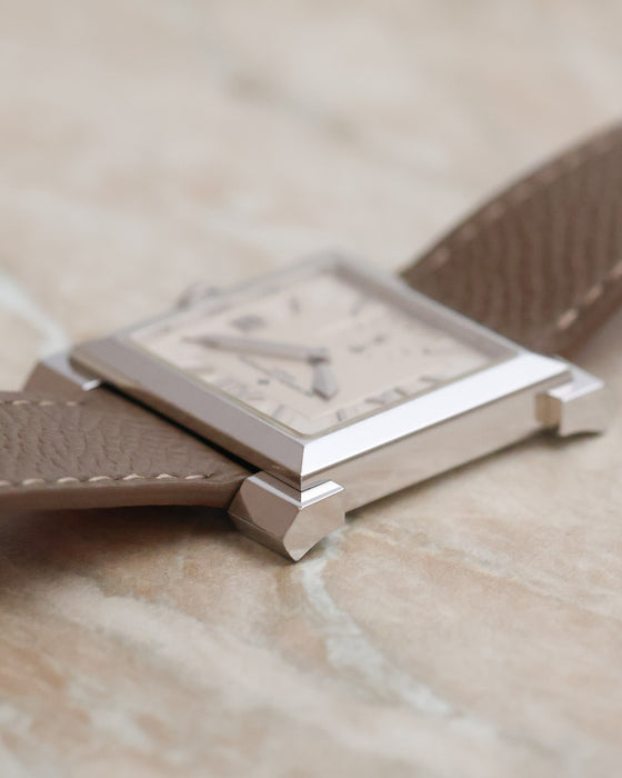 Low-angle photograph emphasising the slim profile and faceted corner lugs of the 18K white gold Carrée Historique.