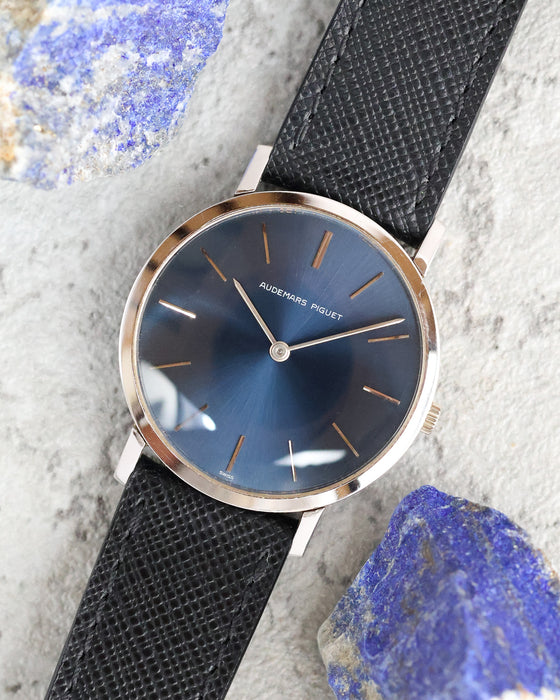 Angled overhead view of an Audemars Piguet blue dial watch photographed alongside blue mineral stones.