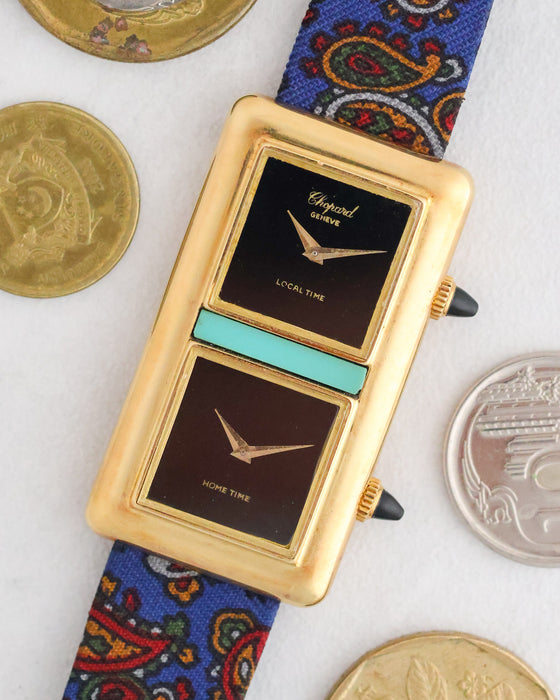 Angled front view of the Chopard Kutchinsky Dual Time beside coins highlighting its onyx dials and turquoise centrepiece.