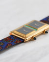 Close-up side view of the dual black-tipped winding crowns on the 18K yellow gold case.