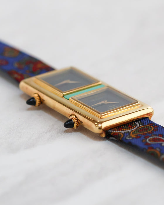 Angled view showing the two separate dial assemblies, turquoise centrepiece and double crowns.
