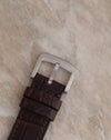 Close-up of the brown leather watch strap and stainless steel pin buckle.
