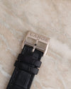 Close-up of the engraved A. Lange & Söhne white gold pin buckle on a black leather strap.