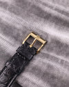 Detail of the original Piaget-signed 18K yellow gold buckle, attached to a black leather strap.